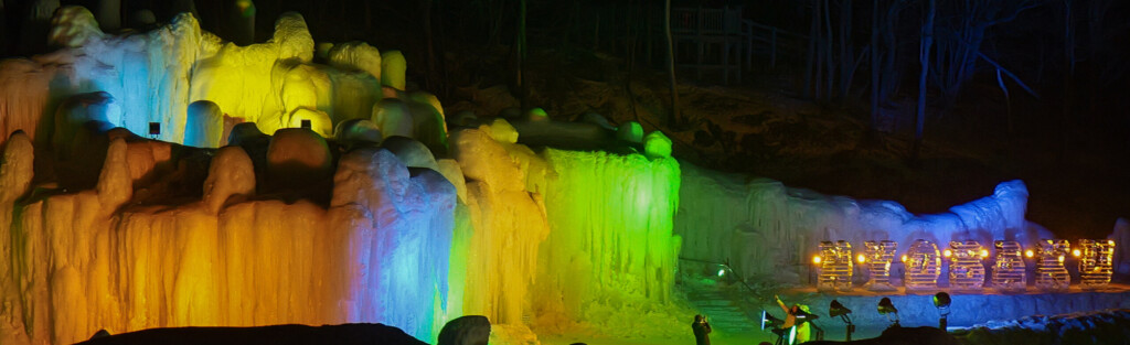 層雲峡温泉 氷瀑まつり2026の会場全景。氷像がカラフルにライトアップされた夜の石狩川河川敷