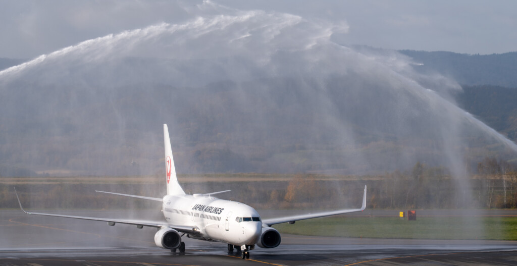 旭川空港に到着し、放水アーチの下を進むJAL2111便
