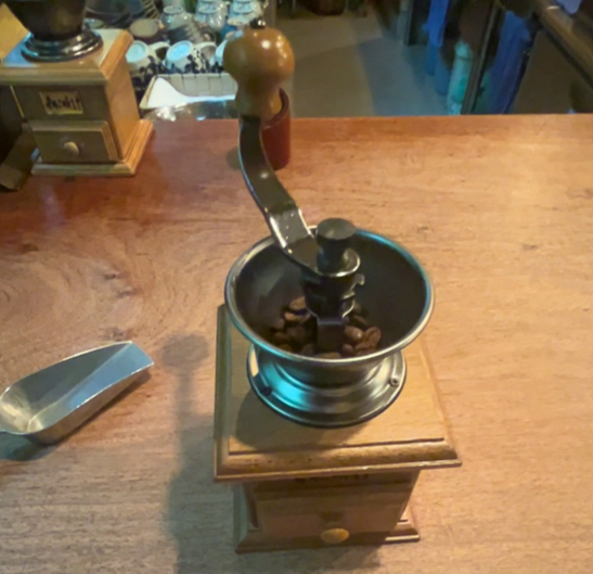 木のカウンターに置かれた、コーヒー豆の入った手挽きミル