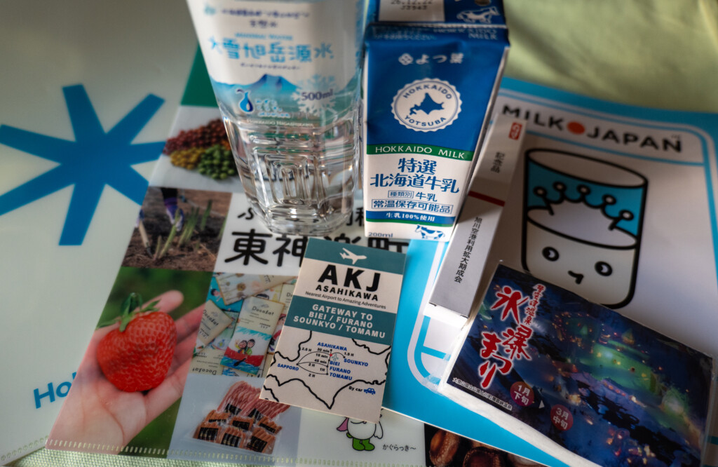 記念品の水や牛乳と、東神楽町や層雲峡などの観光案内資料